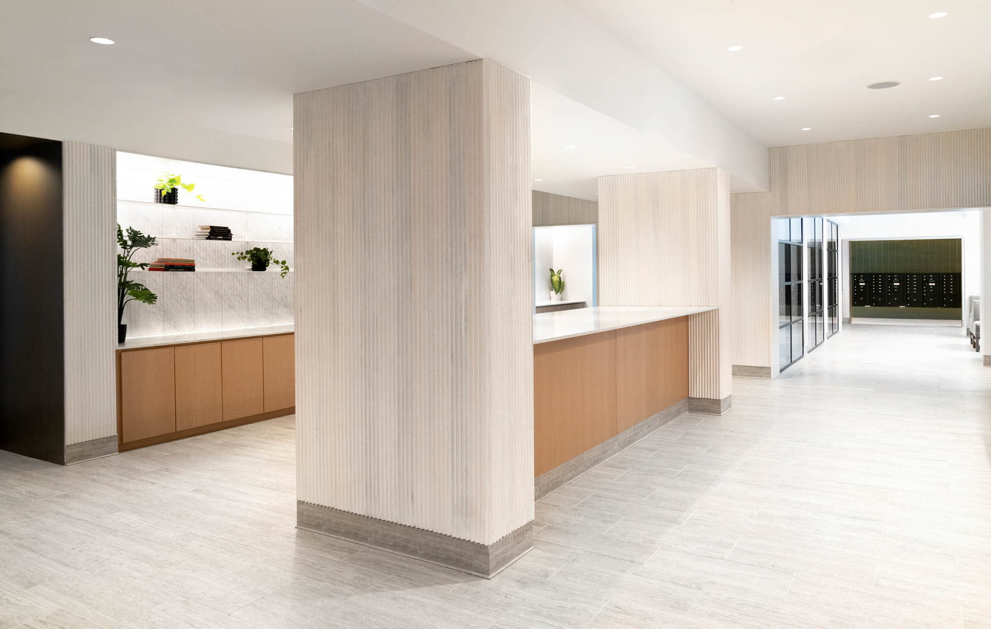 A large kitchen and entertainment space, with white counters, marble pillars sectioning off the kitchen leading to more space further back